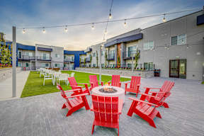 an outdoor patio with red chairs and a fire pit