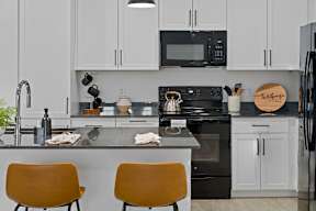 A kitchen with black appliances and white cabinets.