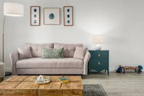 A living room with a couch, a coffee table, and a lamp.