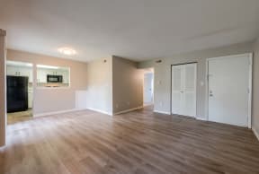 an empty living room with wood floors and white walls