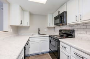 a kitchen with white cabinets and a black stove and microwave