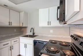 an empty kitchen with white cabinets and a stove top oven