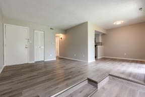 the living room and kitchen of an empty apartment with wood floors