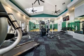 a gym with weights and cardio equipment in a building with green walls