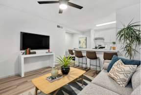 A living room with a grey couch, a wooden table, and a television on a white stand.