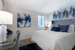A bedroom with a white bed and blue pillows.