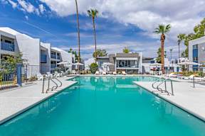 A swimming pool surrounded by palm trees and modern buildings.