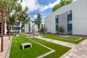 A white bench sits on a green lawn in front of a white building with blue trim.