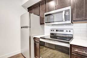 A kitchen with a white refrigerator, stainless steel oven, and microwave.