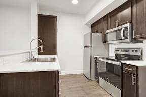 A kitchen with a sink, stove, and refrigerator.