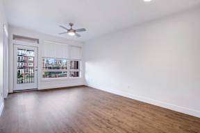 A room with a ceiling fan and a door leading to a balcony.