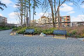 A gravel area with two benches in front of a building.