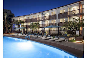 A swimming pool in front of a hotel at night.