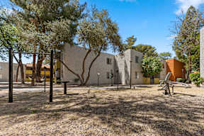 a park with a playground and trees in front of a building