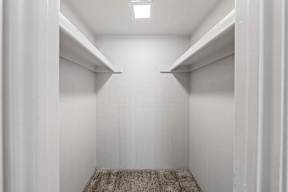 a walk in closet with white walls and white shelves