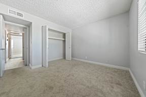Studios In Tempe, AZ - Villatree Apartments - Bedroom With Plush Carpet Flooring, A Spacious Closet, And Window For Natural Light