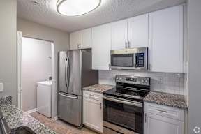 A kitchen with a refrigerator, microwave, oven, and stove.