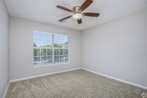 A room with a ceiling fan and a window with blinds.