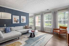 A living room with a grey couch, a round table, and a wooden chair.