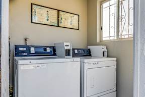 Two washing machines are in front of a wall with a control panel.