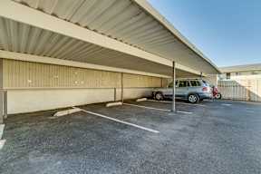 A parking lot with a car parked under a covered area.