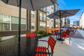 an outdoor patio with red chairs and umbrellas at the cardinal apartments in downtown at Mockingbird Flats, Dallas, TX