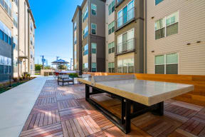 an outdoor patio with a ping pong table in front of an apartment building at Mockingbird Flats, Texas
