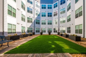 a courtyard with grass and a bench in front of a building at Mockingbird Flats, Dallas, TX