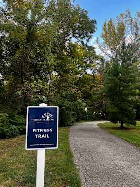 A sign for a fitness trail is on the side of a road.