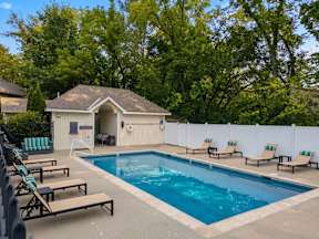 A pool with a white building and lounge chairs.