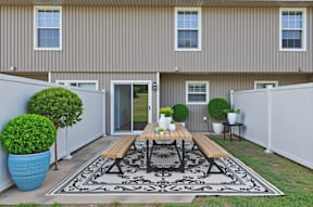 A patio with a table and chairs is surrounded by a white fence.