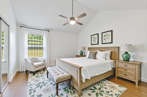 A bedroom with a bed, bench, and two framed pictures on the wall.