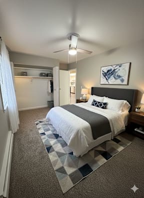 A bedroom with a bed, a ceiling fan, and a rug.