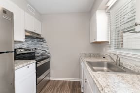 a kitchen with white cabinets and a stainless steel sink