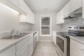 a kitchen with white cabinets and a window