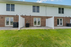 a white building with two white doors and a grassy area in front of it