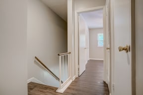 a hallway in a home with gray walls and a wooden floor