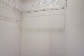 a wire shelf in a white room with a shadow on the wall