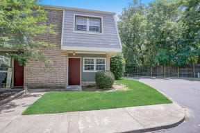 a brick house with a gray roof and a lawn in front of it
