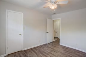 a bedroom with white walls and a ceiling fan