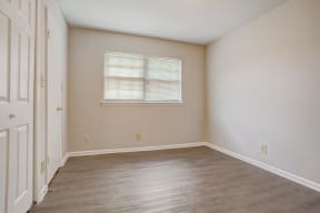 a bedroom with hardwood floors and beige walls