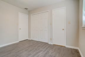 an empty bedroom with two doors and a window