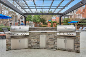 the outdoor kitchen has stainless steel appliances and a stone wall with two grills at Madison Brookhaven, Georgia, 30329