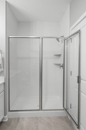 a white bathroom with a shower and glass doors