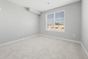 an empty room with a large window and carpet