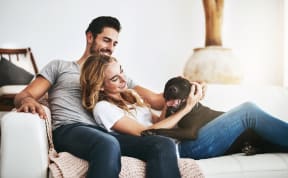 a man and woman sitting on a couch with a dog
