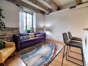 A living room with a purple couch and a yellow chair.