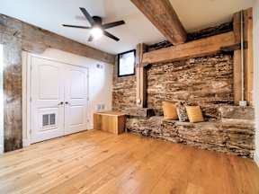 A room with a white door and a stone wall.