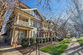 A row of houses with a sidewalk in front.