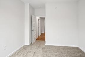 A hallway with a carpeted floor and white walls.